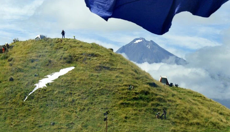 Parihaka Peace Festival, Parihaka with Mount Taranaki in the distance and giant white feather on the side of a neighbouring hill.