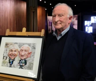 Ian Grant with a framed caricature of himself and his wife. 