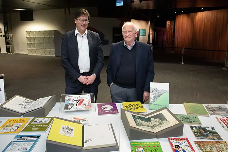Two men looking at a display of books open on a table.