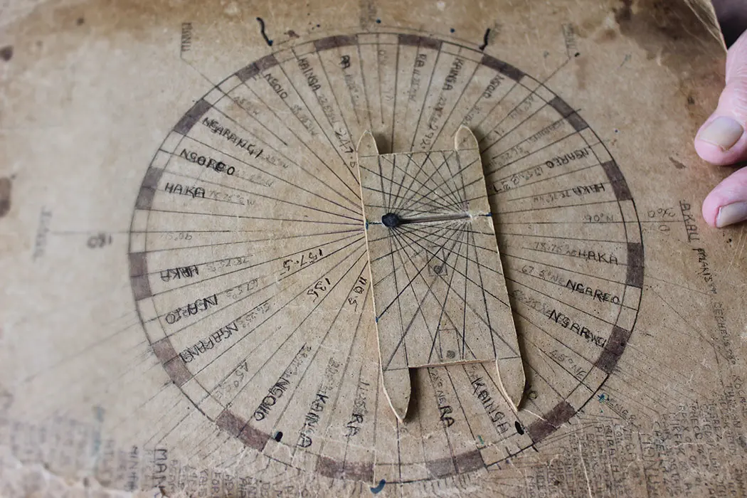 Colour photograph of Tā Hec’s compass showing a waka in the center and dial lines of the stars, sun, and moon locations.