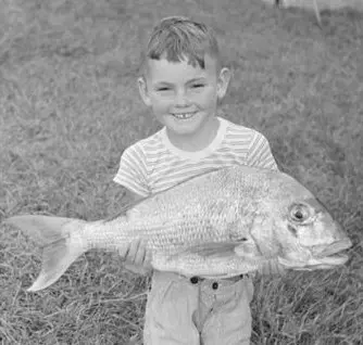 A young boy holding a large fish.