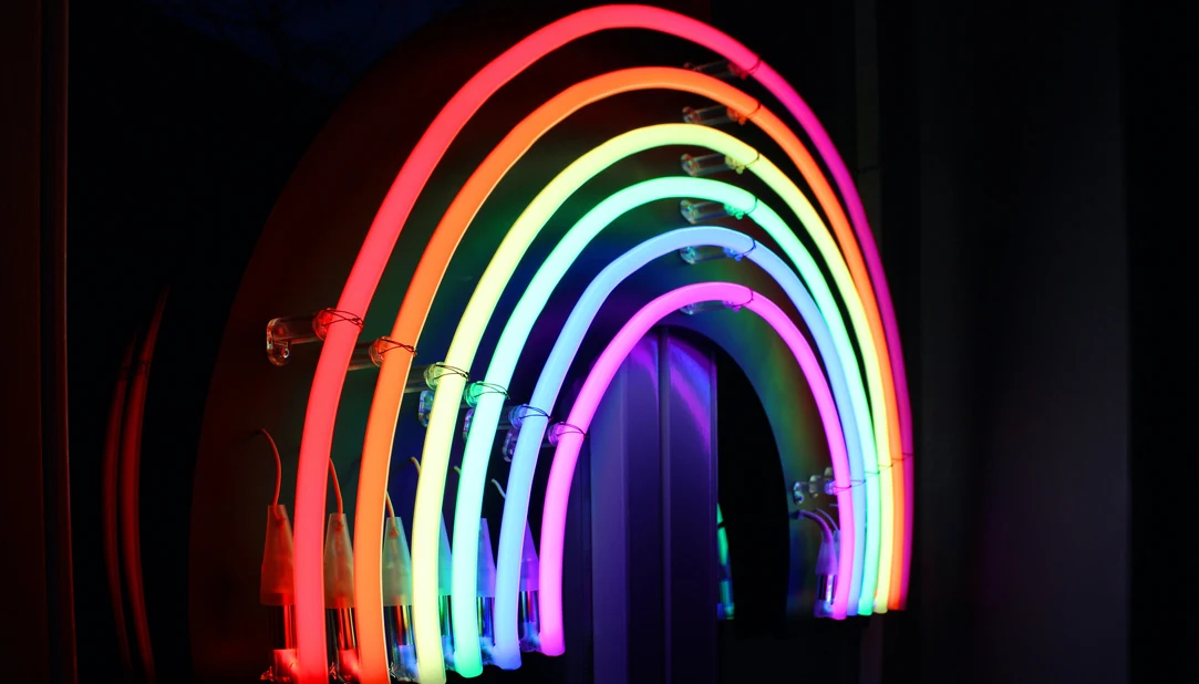 An arch of rainbow coloured lights against a black background. 