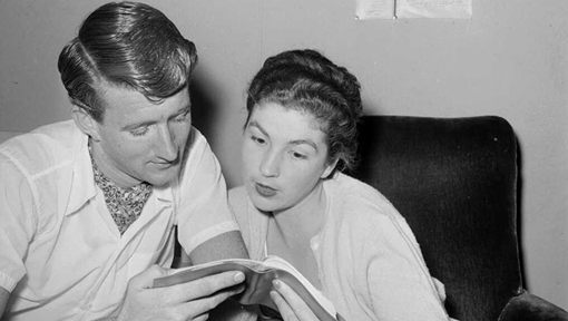 Black and white photo of a man and woman reading a book together. 