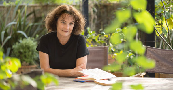 Kate De Goldi sitting at a table in a garden.