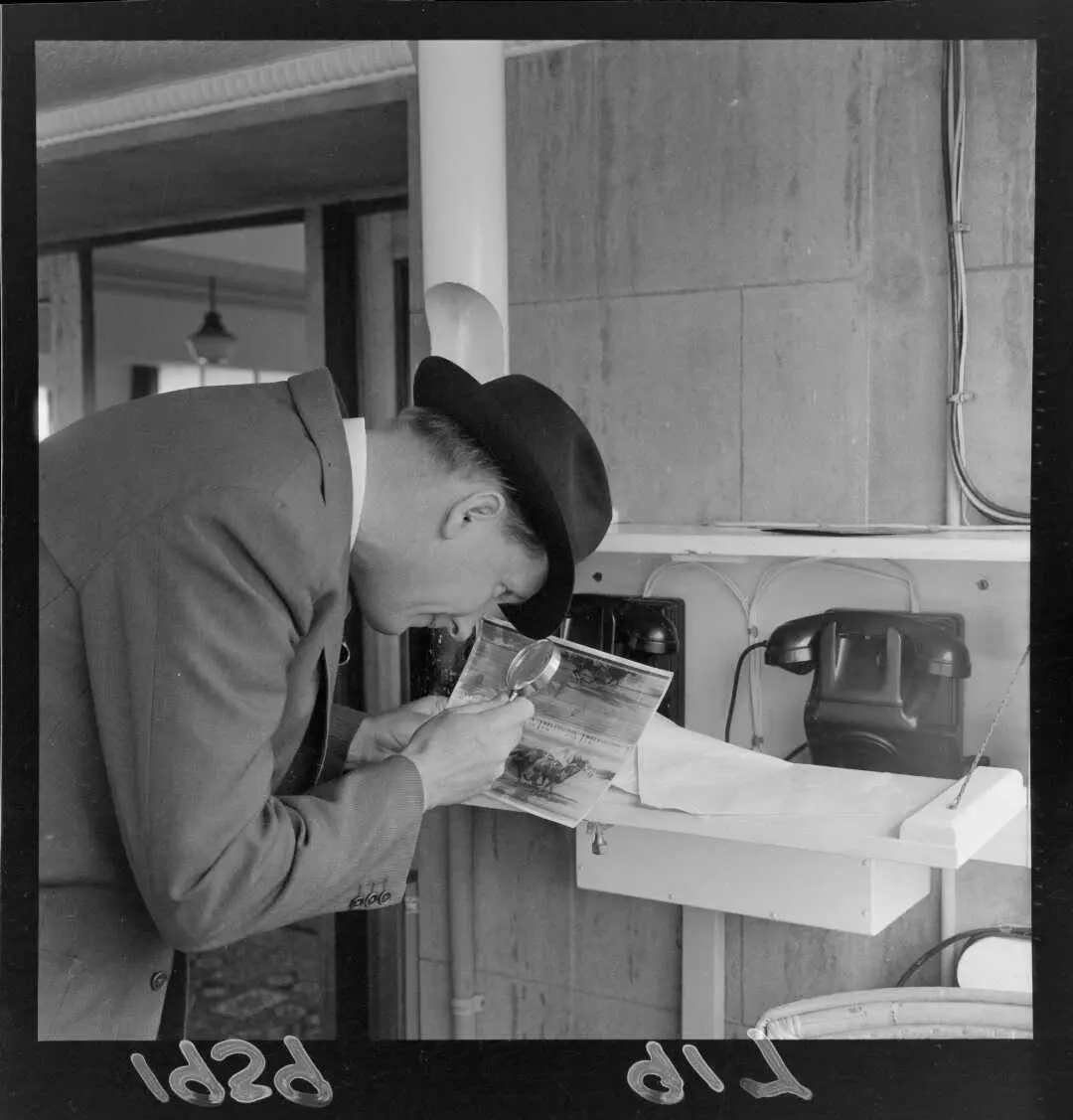 Unidentified man inspecting a photo finish record with a magnifying glass