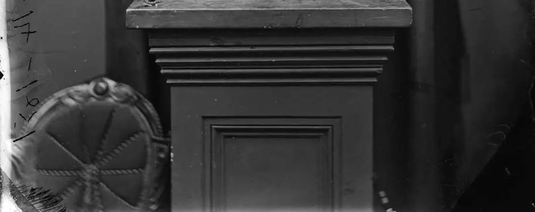 A wooden plinth with a chair with a round padded back next to it.