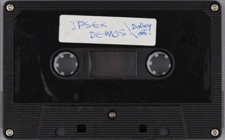 Black cassette tape with white label with handwritten title.