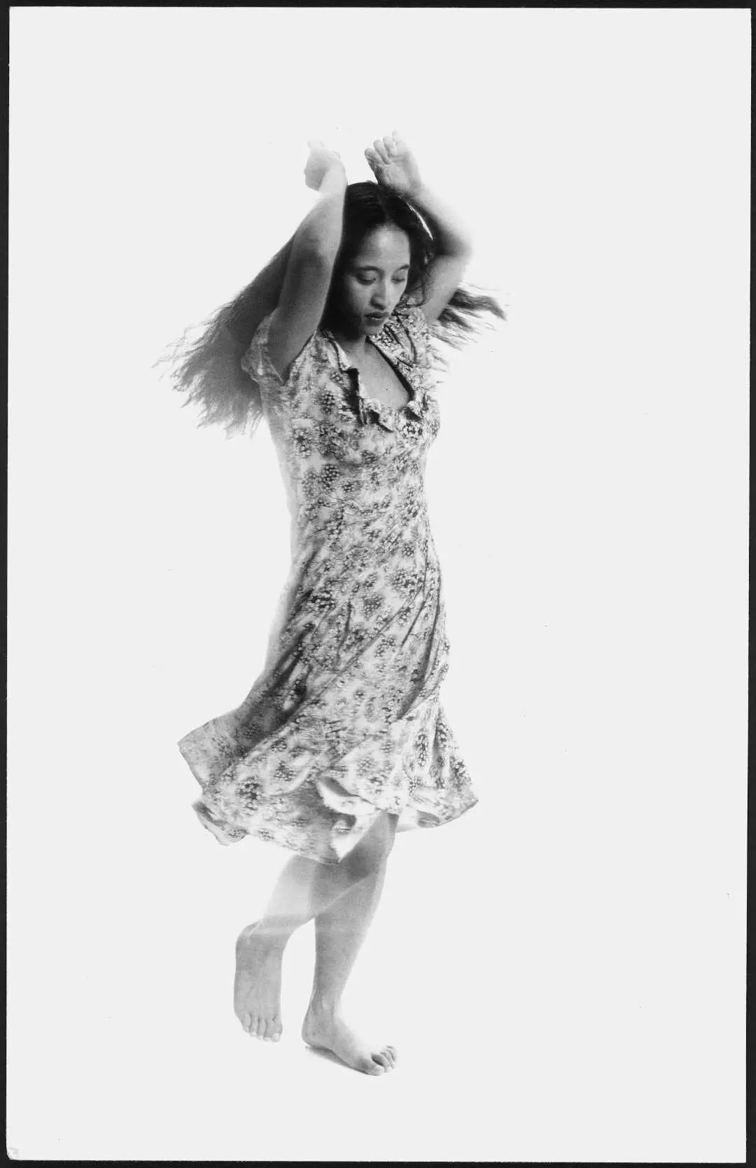 A woman with her arms above her head dancing. Her dress is swooshing around her.