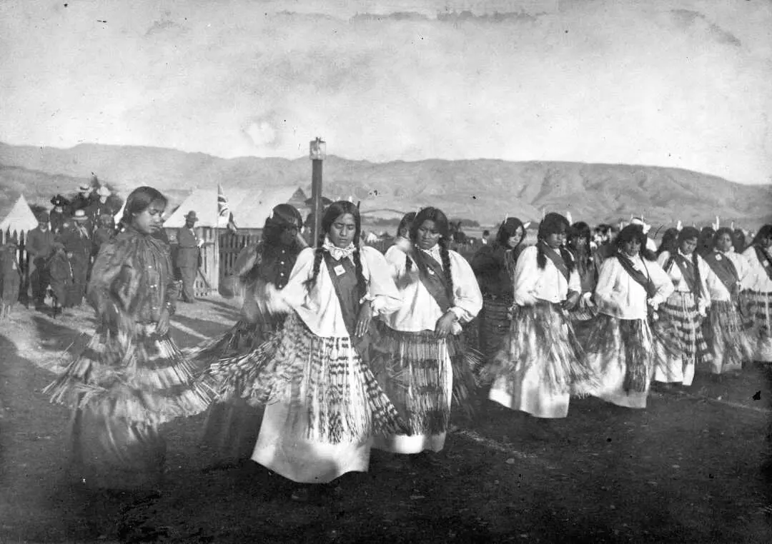 A line of women moving so that their piupiu are swinging around them. 