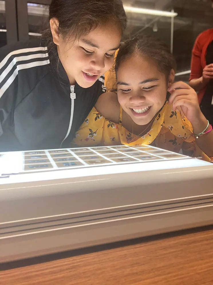 Two smiling girls looking at photographic negatives.