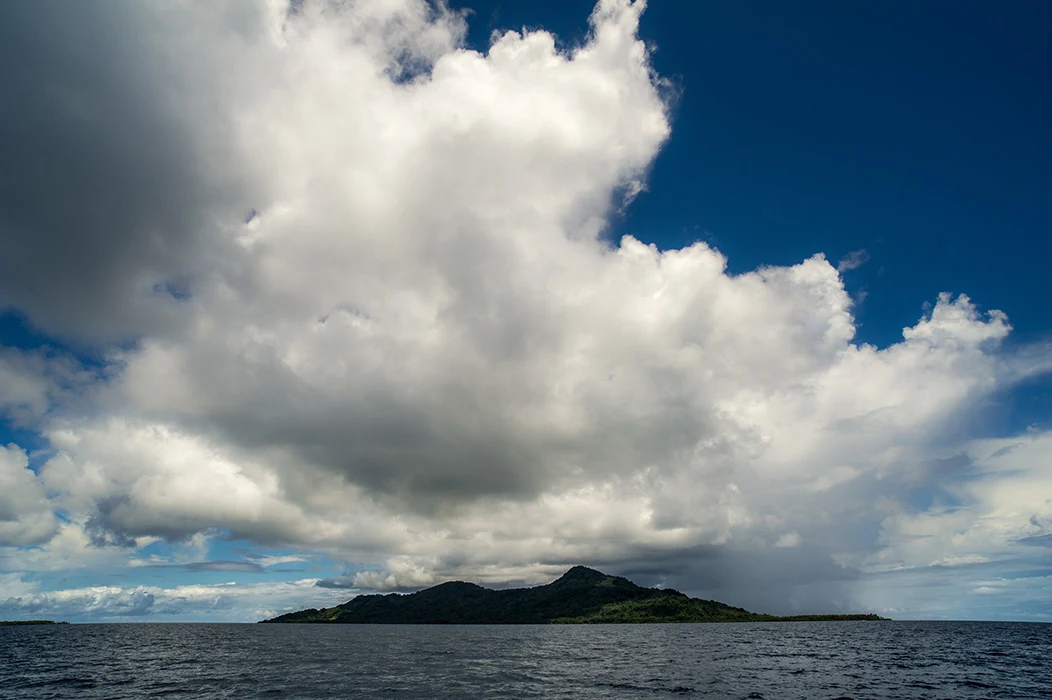Colour photograph showing clouds above an island.