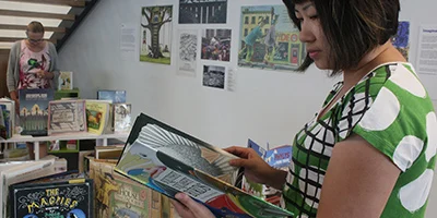 A school loan coordinator teacher browsing through books in a library.