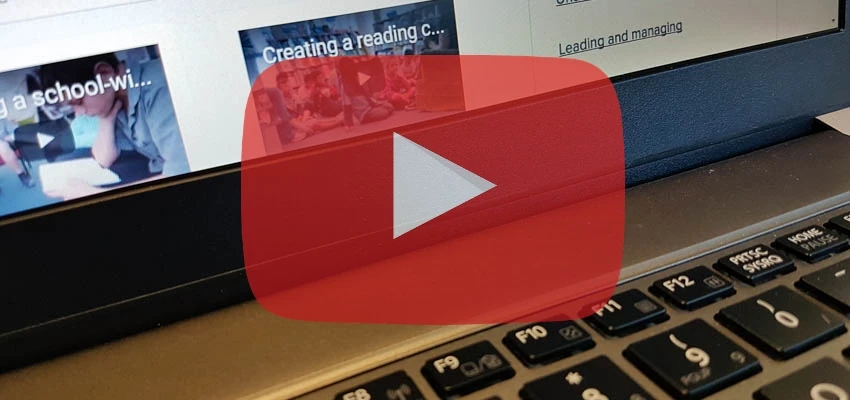 Red and white video play icon superimposed over a laptop keyboard and screen.