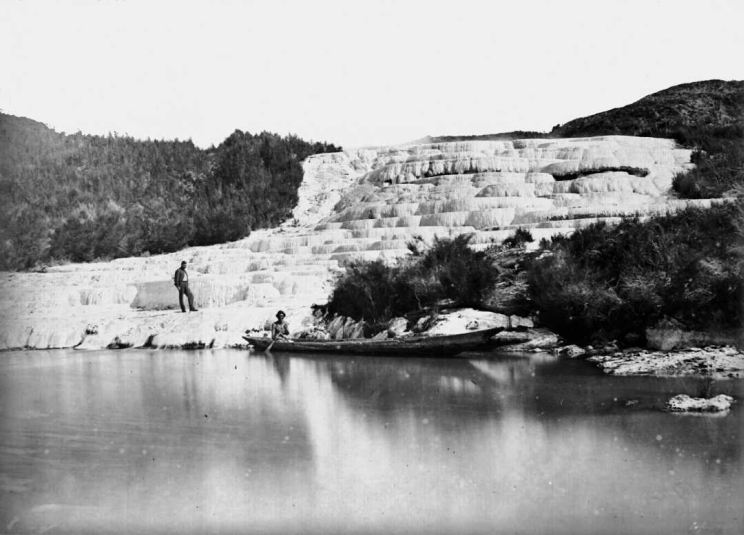 A black and white photo of the Pink Terraces with a boat and two men in the frame.