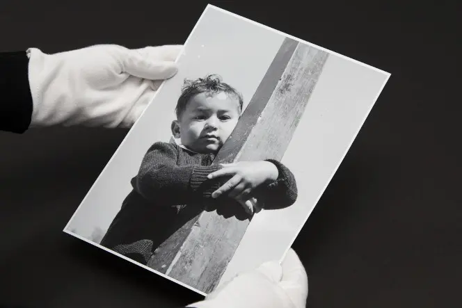 Gloved hands holding a photograph of a young Māori boy