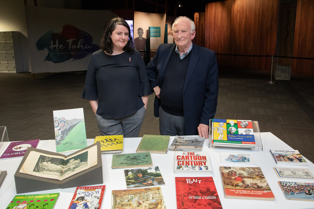 Hannah and Ian standing behind a table covered with different books.