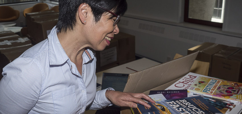 Person smiling as she looks at some new books on a table.