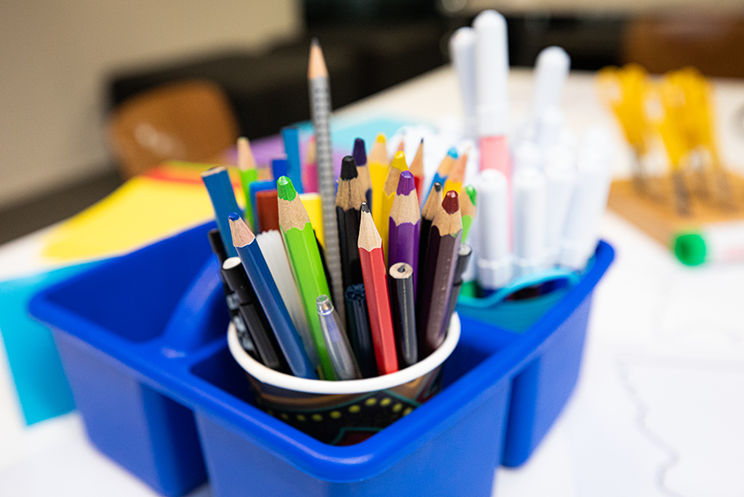 Blue container holding pencils and craft material.
