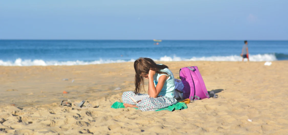 Girl reading a book on the beach