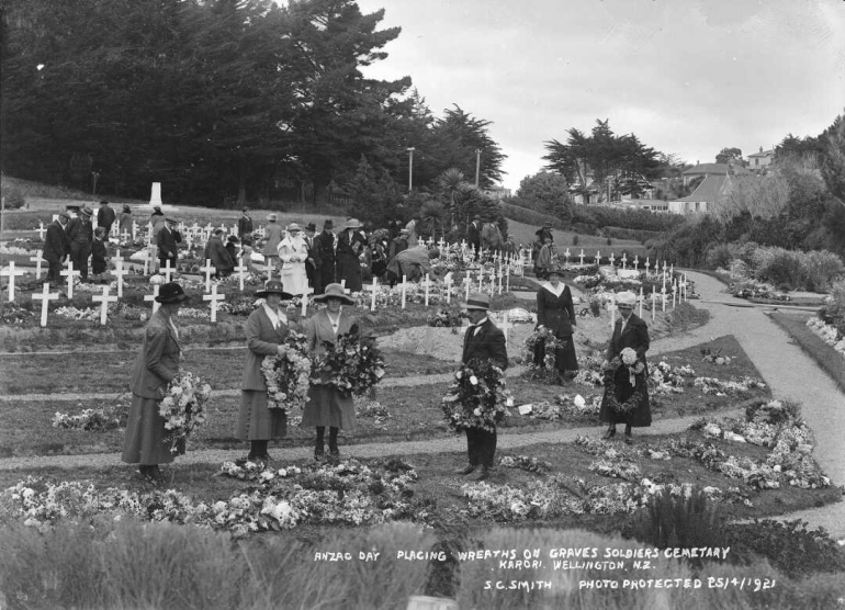 Men and women placing wreaths on the ground where graves are marked at Karori cemetery.