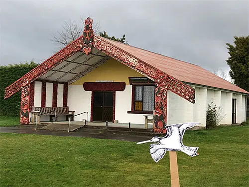 Colour photograph of a kuaka (bar-tailed godwit) cut out held in front of Rākautātahi marae.