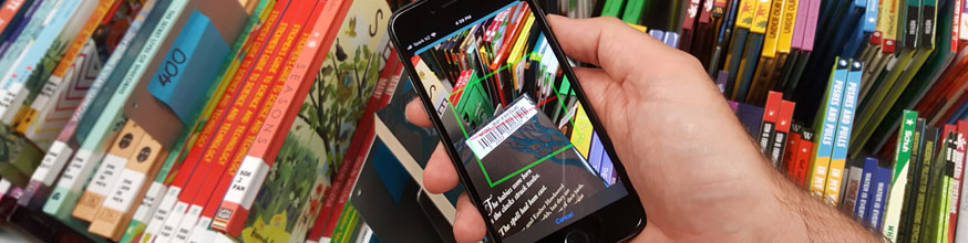 Hand holding mobile phone scanning a barcode on a book. 