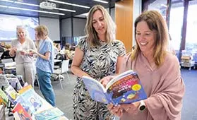 Teachers looking at books on display at a workshop.