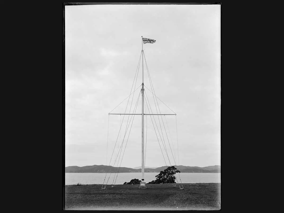 Black and white photo of the flagstaff marking the spot where Te Tiriti o Waitangi | Treaty of Waitangi was first signed. In the background is a view across the Bay of Islands.
