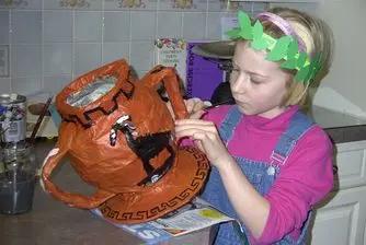 A girl painting a greek pot.