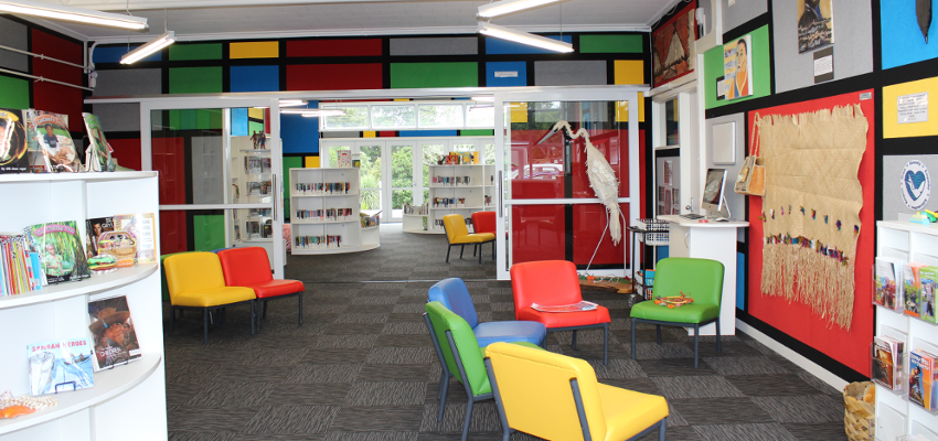 Colourful school library with chairs and bookshelves.