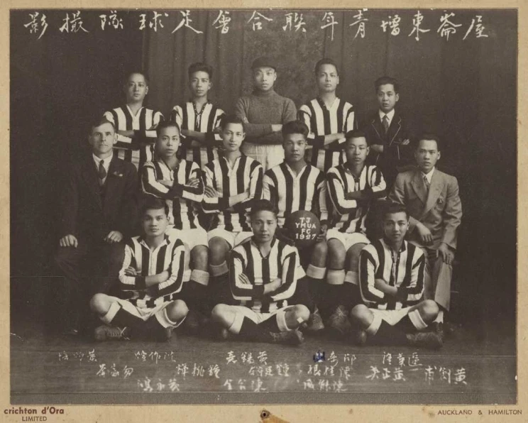 Formal group portrait with young men in black and white striped uniforms.