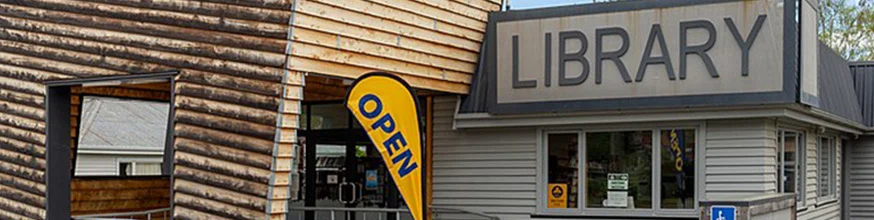 Exterior of a library with large library sign and a open banner.