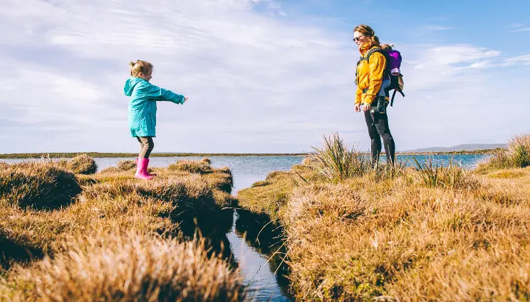 Girl and mother walking on grassy estuary