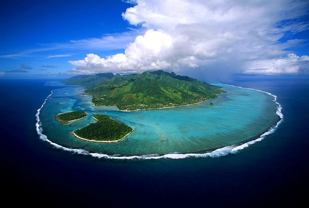 Colour photograph showing an aerial view of Moorea island with surrounding clouds and blue ocean.