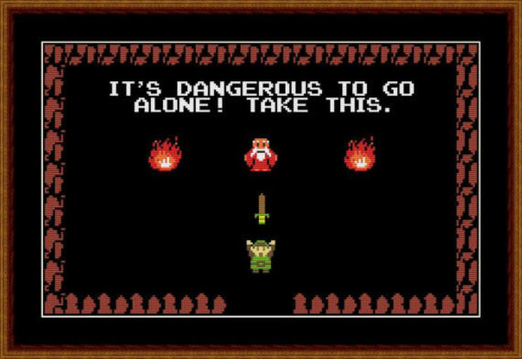 A video game, there is a brown perimeter with one gap, inside the perimeter are the words "It's dangerous to go alone! as well as two fires, a bearded man and a sword. A small green creature is walking through the gap. 