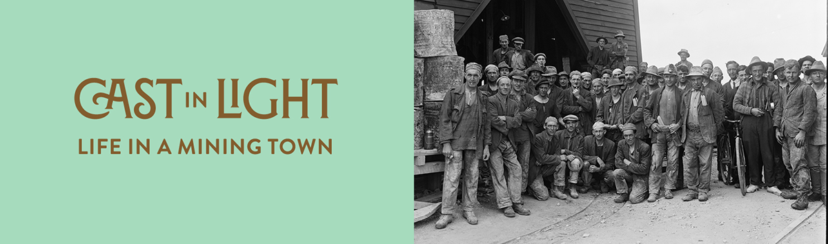 Words Cast in light, life in a mining town and a black and white photo of a large group of men at the top of a mine shaft. 