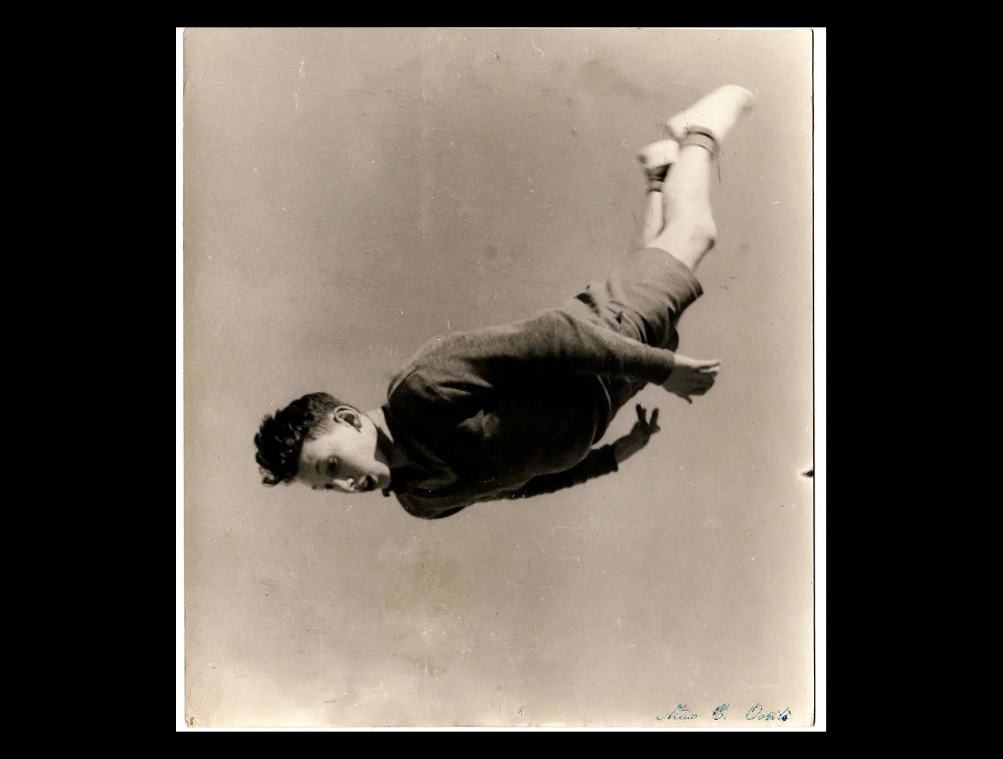 Black and white photo of a student in uniform diving headfirst in mid-air.
