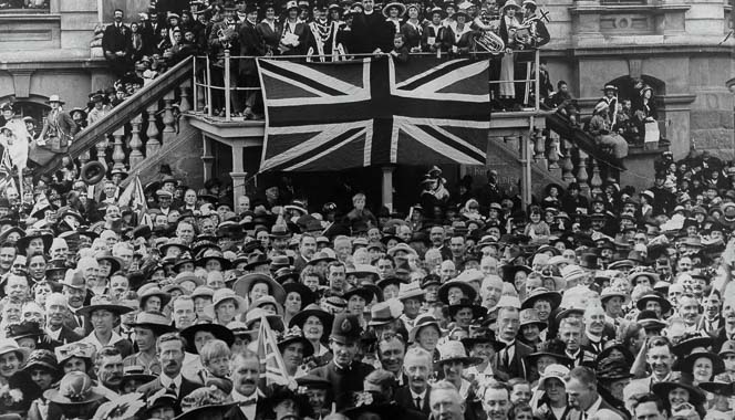 Armistice Day crowd celebrating in Dunedin with Union Jack flag.