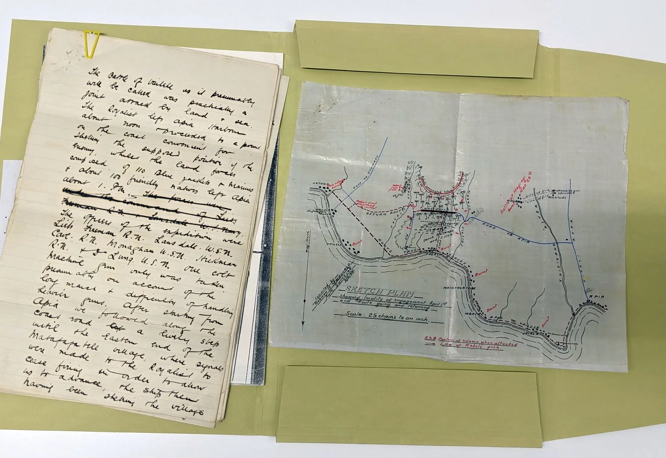 An open folder with a reproduction of a hand-drawn map on the right and a yellowed page of handwritten text on the left. 