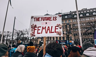 Women protesting, one holding a banner saying 'The future is female'.