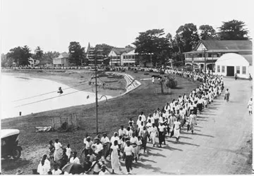 A long line of people from the Mau movement in Apia marching down a coastal road.