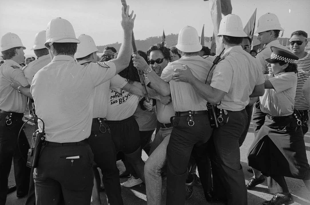 Black and white photo of Ben Dalton being restrained by police in uniform and helmets.