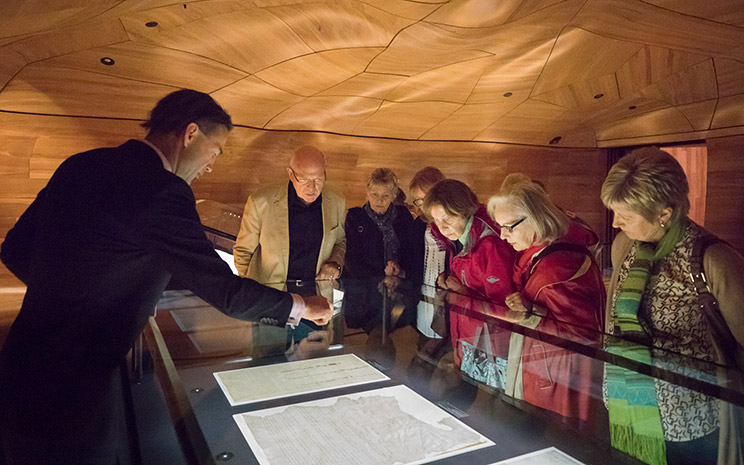 A group of people doing a tour of He Tohu and looking at some of the Treaty of Waitangi sheets.
