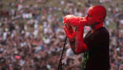 NZ artist Tiki Taane blowing on a conch shell while performing live.