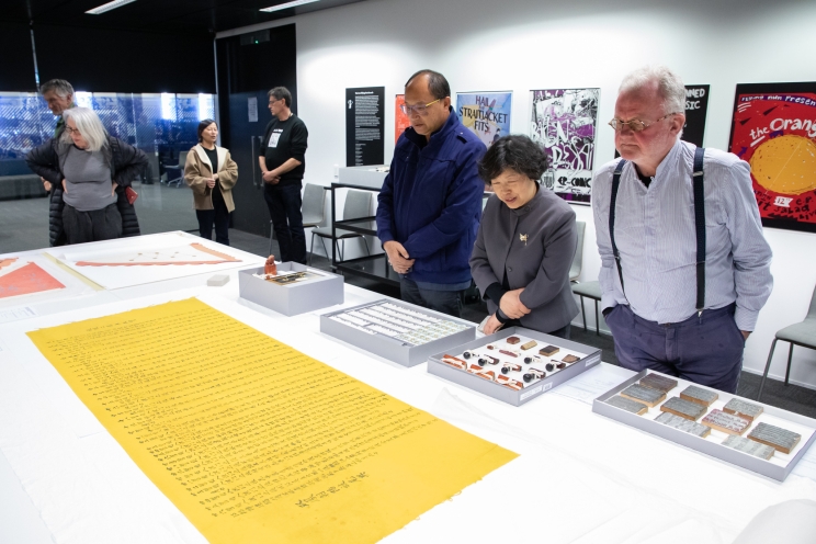 Shows collection items displayed on a table while a couple of visitors view them.