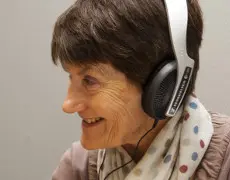 A woman wearing headphones, taking part in oral history training.