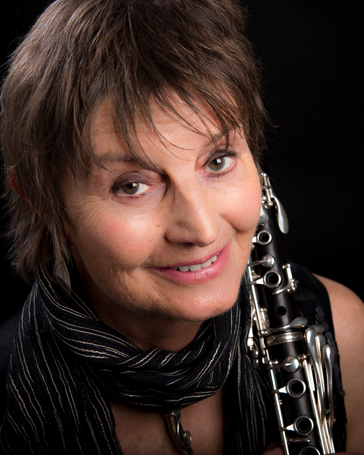 Head shot of a woman holding a flute over her shoulder.