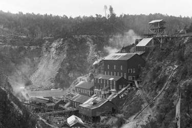 Black and white photo of a mine battery and buildings built up a hillside.