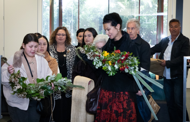A family group stand together with two members holding large bunches of flowers which were given as part of a ceremony.