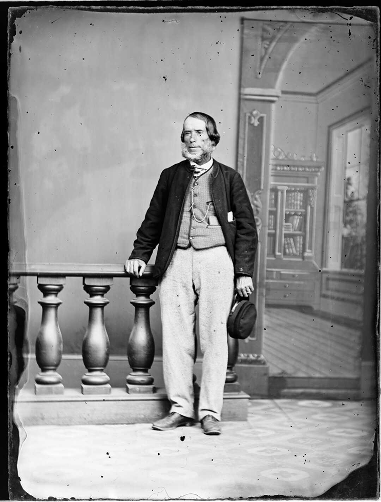 Victorian era studio image of a man standing with a background. 